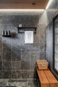 a bathroom with a black tiled wall and a wooden bench at Nilirakka - Luxury log Chalet in Levi in Levi