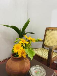 un jarrón con flores amarillas en una mesa junto a una silla en Shiv's Villa, en Unawatuna