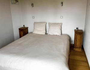 ein weißes Bett in einem Zimmer mit zwei Kissen in der Unterkunft Gîte trois étoiles, maison de campagne in Fiac