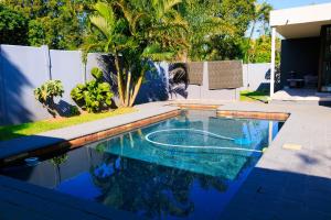 a swimming pool in a backyard with a palm tree at Mbuso Guest Lodge in Richards Bay