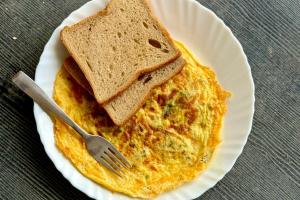 a white plate with an omelet and two slices of toast at Aqua Wave by YogiTree Hotels in North goa +41 photos