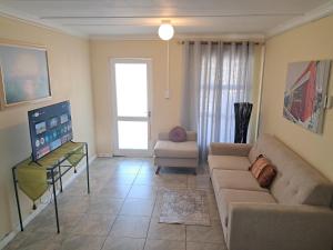 a living room with a couch and a tv at Deo Volente Self-Catering Cottage in Kuilsrivier