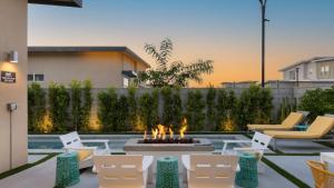 a patio with chairs and a fire pit with a fire burns at Lumen at Tahquitz: New Build with Pool Fire Pit Designer Interiors in Palm Springs