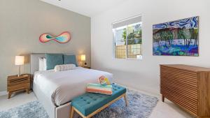 a bedroom with a bed with a blue bench and a painting at Lumen at Tahquitz: New Build with Pool Fire Pit Designer Interiors in Palm Springs +26 photos