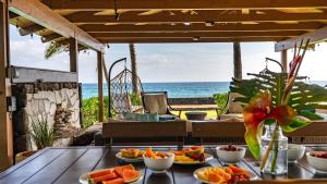 a table with plates of fruit on it with the ocean in the background at Turtle House by AvantStay Oceanfront Group Retreat w Patio Views in Waianae
