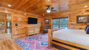 ein Blockhütten-Schlafzimmer mit einem Bett und einem Flachbildfernseher in der Unterkunft Big Bear Cove by AvantStay Hot Tub Game Room Fireplace Smoky Mtn Views in Sevierville