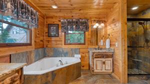 ein Badezimmer mit einer Badewanne und einem Waschbecken in der Unterkunft Big Bear Cove by AvantStay Hot Tub Game Room Fireplace Smoky Mtn Views in Sevierville + 33 Fotos
