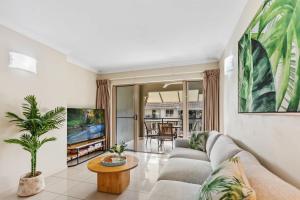 een woonkamer met een bank en een tv bij Cairns 2BR Palms Stay Top Floor & Pool View in Westcourt