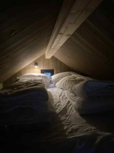 a bed with white sheets and pillows in a room at Gjeterhytta in Stavanger