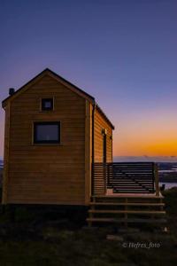 a small wooden house with a sunset in the background at Gjeterhytta in Stavanger +8 photos