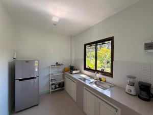 cocina con nevera, fregadero y ventana en Modern Nature Retreat, en Ko Pha Ngan