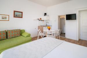 a living room with a green couch and a table at Studio Apartments Cavrak with Terrace in Baška