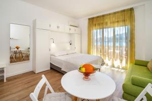 a bedroom with a bed and a table and a couch at Studio Apartments Cavrak with Terrace in Baška