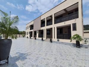 a building with a courtyard with palm trees in front at Cosdarl Homes in Nsawam