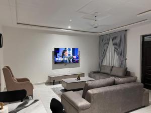 a living room with a couch and a tv on the wall at Cosdarl Homes in Nsawam