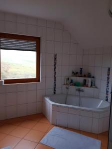 ein weißes Badezimmer mit Badewanne und Fenster in der Unterkunft Ferienhaus mit Terrasse in Bruck in der Oberpfalz