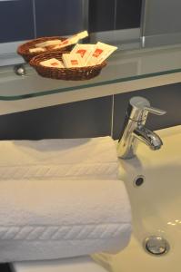 a bathroom sink with towels and a basket on a counter at B&B Cous Cous People in San Vito lo Capo