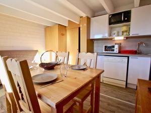 una cucina con tavolo in legno e piatti di Studio cabine avec parking couvert à Chamrousse - FR-1-340-122 a Chamrousse