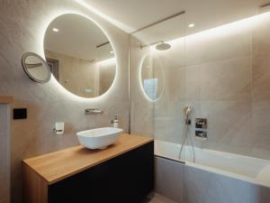 ein Badezimmer mit Waschbecken, Spiegel und Badewanne in der Unterkunft Chalet 5★, 10 pers, spa extérieur & sauna, à 230m des pistes - FR-1-304-282 in La Clusaz + 16 Fotos