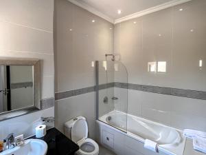 a bathroom with a tub and a toilet and a sink at Golden Crystal Hotel Gaborone in Gaborone +25 photos