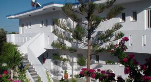 a tree in front of a white building with flowers at Creta Vassakis Studios in Kefalos