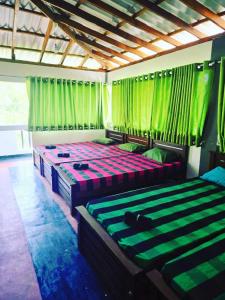 two beds in a room with green curtains at Habarana Guest House in Habarana