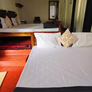 a room with three beds with white sheets and pillows at Habarana Guest House in Habarana