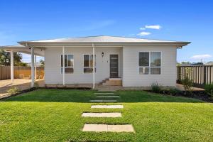 a small white house with a grass yard at Tailem Retreat in Tailem Bend