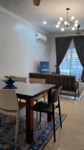 a dining room with a table and chairs and a couch at Homestay Makyu Kuala Kangsar in Kuala Kangsar