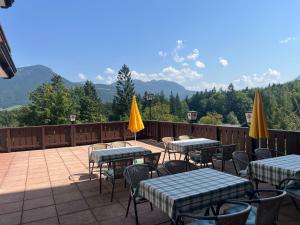 a patio with tables and chairs with mountains in the background at Bergzauber in Bad Goisern