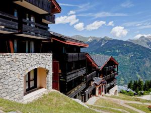 a building on a hill with mountains in the background at Appartement rénové près des pistes avec terrasse, ski, parking et cuisine équipée - FR-1-514-48 in Courchevel