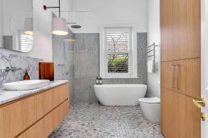 ein Badezimmer mit zwei Waschbecken und einer Badewanne und einer Toilette in der Unterkunft The BeBe on Gover - Heritage Gem in North Adelaide in North Adelaide + 22 Fotos