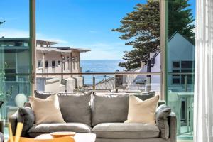 a couch on a balcony with a view of the ocean at Seaview Horizon - Coastal Elegance by Henley Beach in Henley Beach