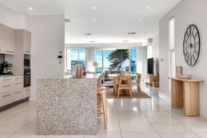 a kitchen and dining room with a large clock on the wall at Seaview Horizon - Coastal Elegance by Henley Beach in Henley Beach