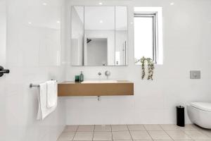 a bathroom with a sink and a toilet and a mirror at Seaview Horizon - Coastal Elegance by Henley Beach in Henley Beach +12 photos