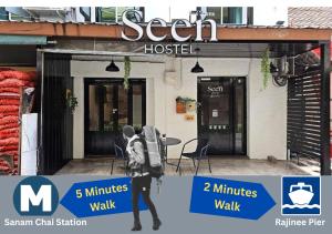 a person with a backpack walking outside of a building at Seen Hostel Bangkok The Riverwalk in Bangkok