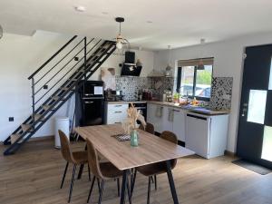 a kitchen and dining room with a table and a staircase at Maison en pierre, proche du Futuroscope in Scorbé-Clairvaux
