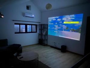a living room with a large screen in a room at Maison en pierre, proche du Futuroscope in Scorbé-Clairvaux