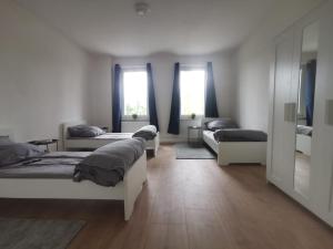 a room with four beds and a couch and windows at Apartmenthaus in Rüdersdorf in Rüdersdorf