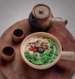a bowl of soup on a wooden table with a pot at DALI FLOWER&CAT VILLa in Dali
