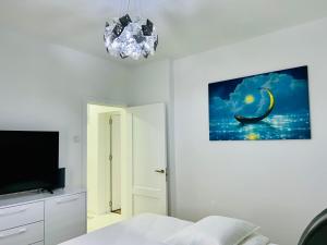 ein Schlafzimmer mit Bett, Fernseher und Kronleuchter in der Unterkunft Blue Queen in Fălticeni