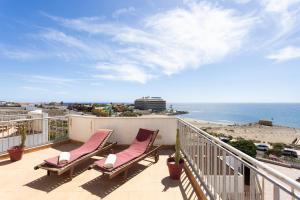 a balcony with two chairs and a view of the beach at Seafront Penthouse in El Medano in El Médano