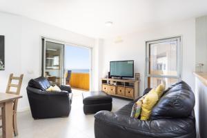 a living room with two leather chairs and a television at Seafront Penthouse in El Medano in El Médano