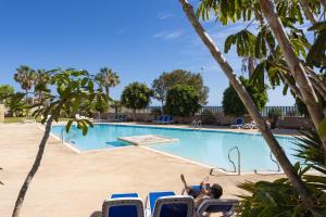a woman laying in chairs in front of a swimming pool at Seafront Penthouse in El Medano in El Médano