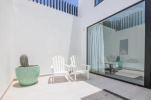 Una habitación con dos sillas blancas y un cactus. en Cascasas the Yellow Apartment, en La Oliva