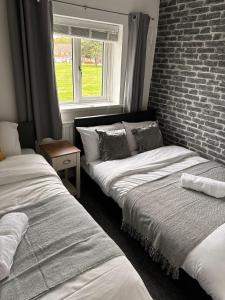 two beds in a room with a brick wall at Tranquil Walsall Retreat - 4 Bedrooms in Bloxwich