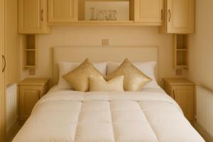 un letto bianco con cuscini dorati sopra di Combe Haven Holiday Park - Holiday Accommodation 12122 a Hollington