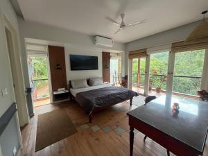 une chambre avec un lit, une table et des fenêtres dans l'établissement Luxury Villa in Wayanad Hills with Private Garden, à Wayanad