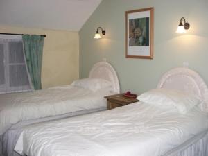 two beds in a room with white sheets at The George Hotel in Newent