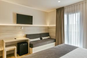 a hotel room with a bed and a desk and a tv at Hotel Emporium - Adults Only in Castelló d'Empúries
